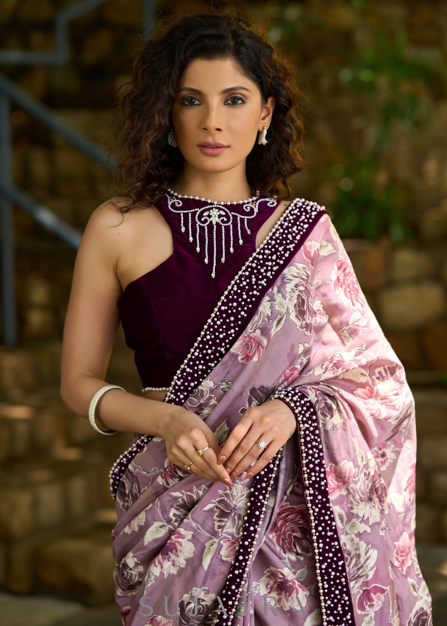 Gracious purple floral printed saree highlighted with velvet pearl embroidered border